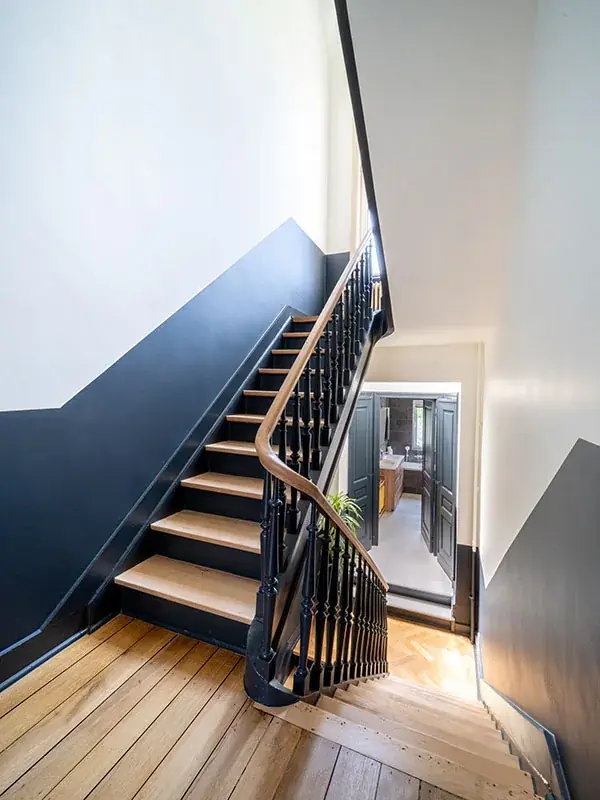 Rénovation de cage d'escalier : montée d'escalier bleu nuit, rampe bois et balustres noirs