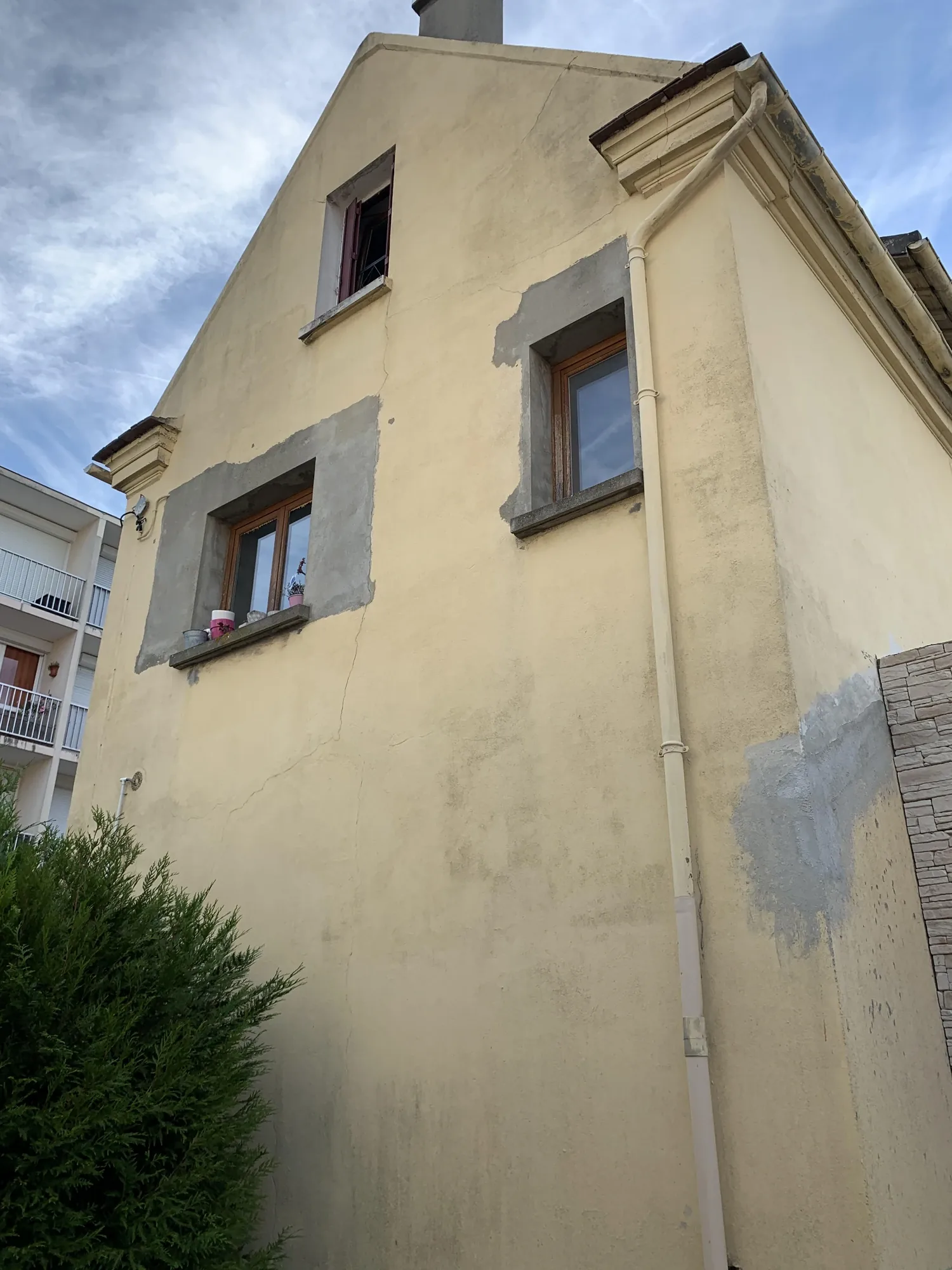 Pignon de la maison avant rénovation à Bezons : fissures, reprises de maçonnerie grises et ancienne peinture