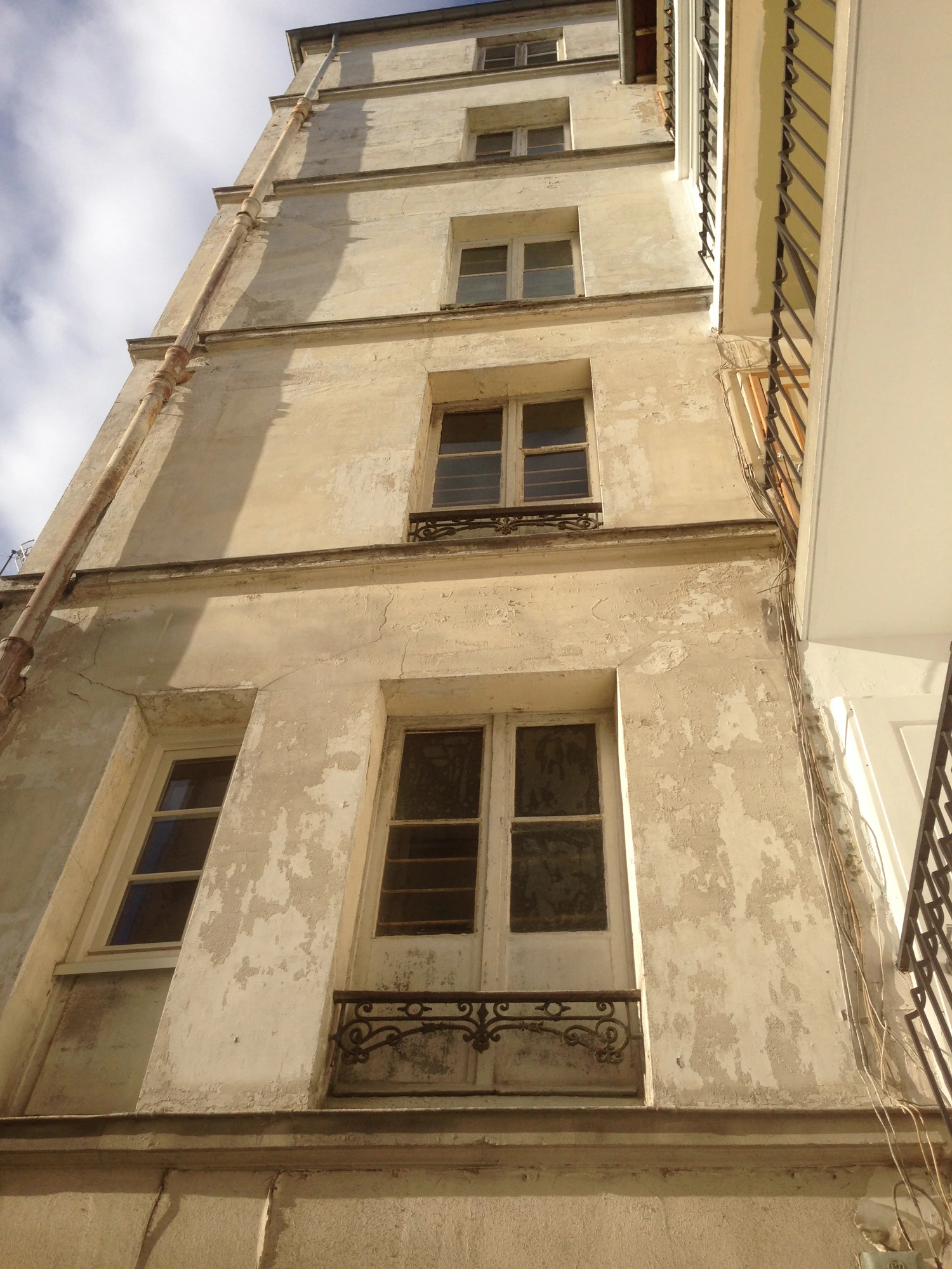 Façade sur cour d'une copropriété à Paris 13e avant ravalement : support très dégradé, fissures et enduit qui s'écaille