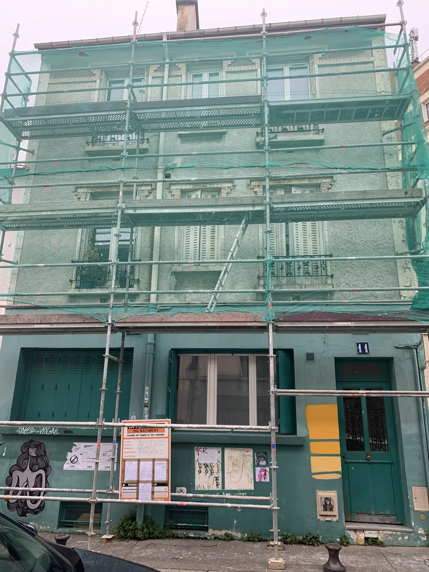 Échafaudage de pied monté sur la façade d'un immeuble à Paris 15e pour le ravalement, avec panneau d'autorisation