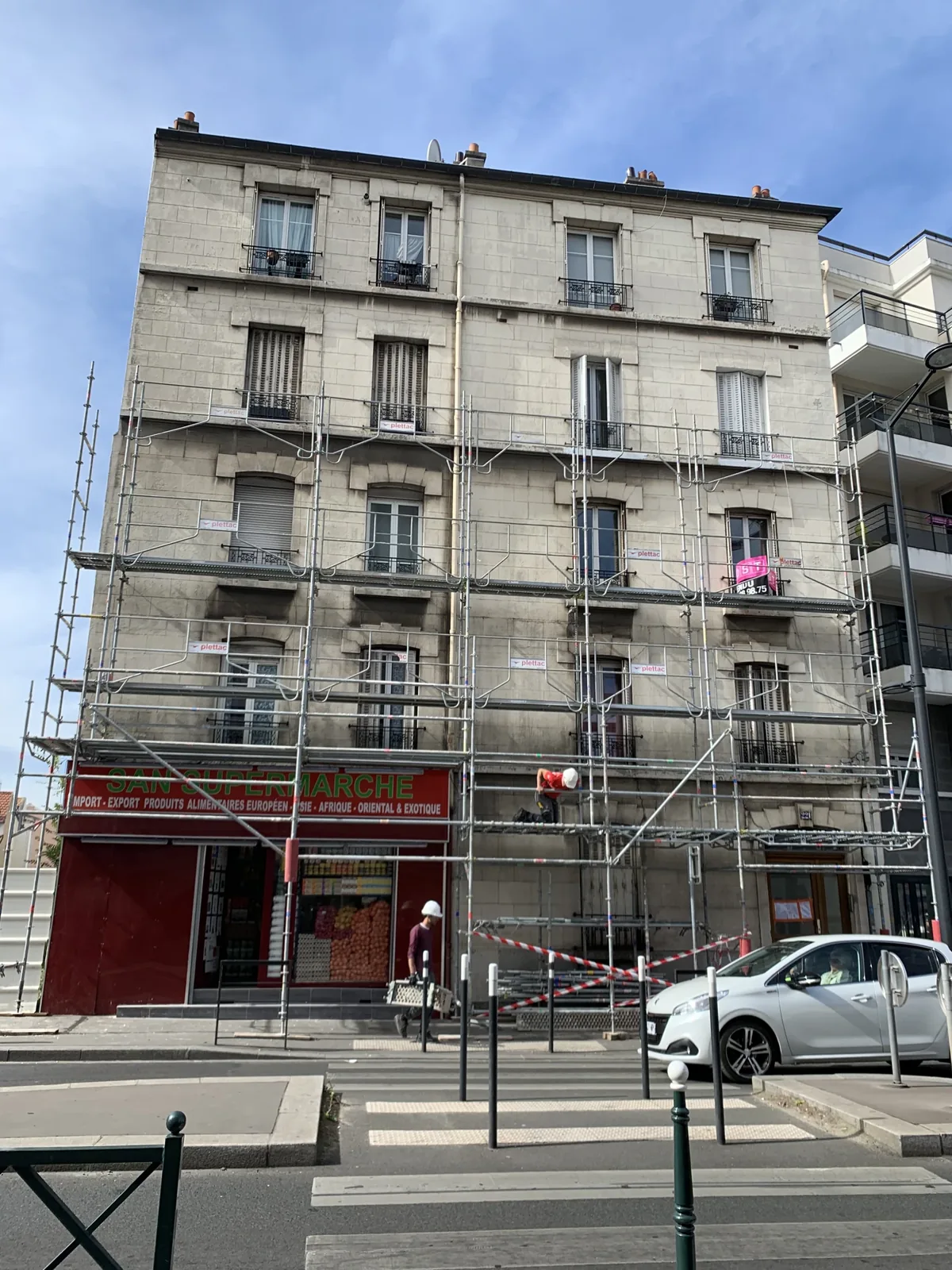 Façade d'une copropriété avant ravalement à Paris 4e, échafaudage installé et ancien enduit ciment peint Façade d'une copropriété avant ravalement à Paris 4e, échafaudage installé et ancien enduit ciment peint