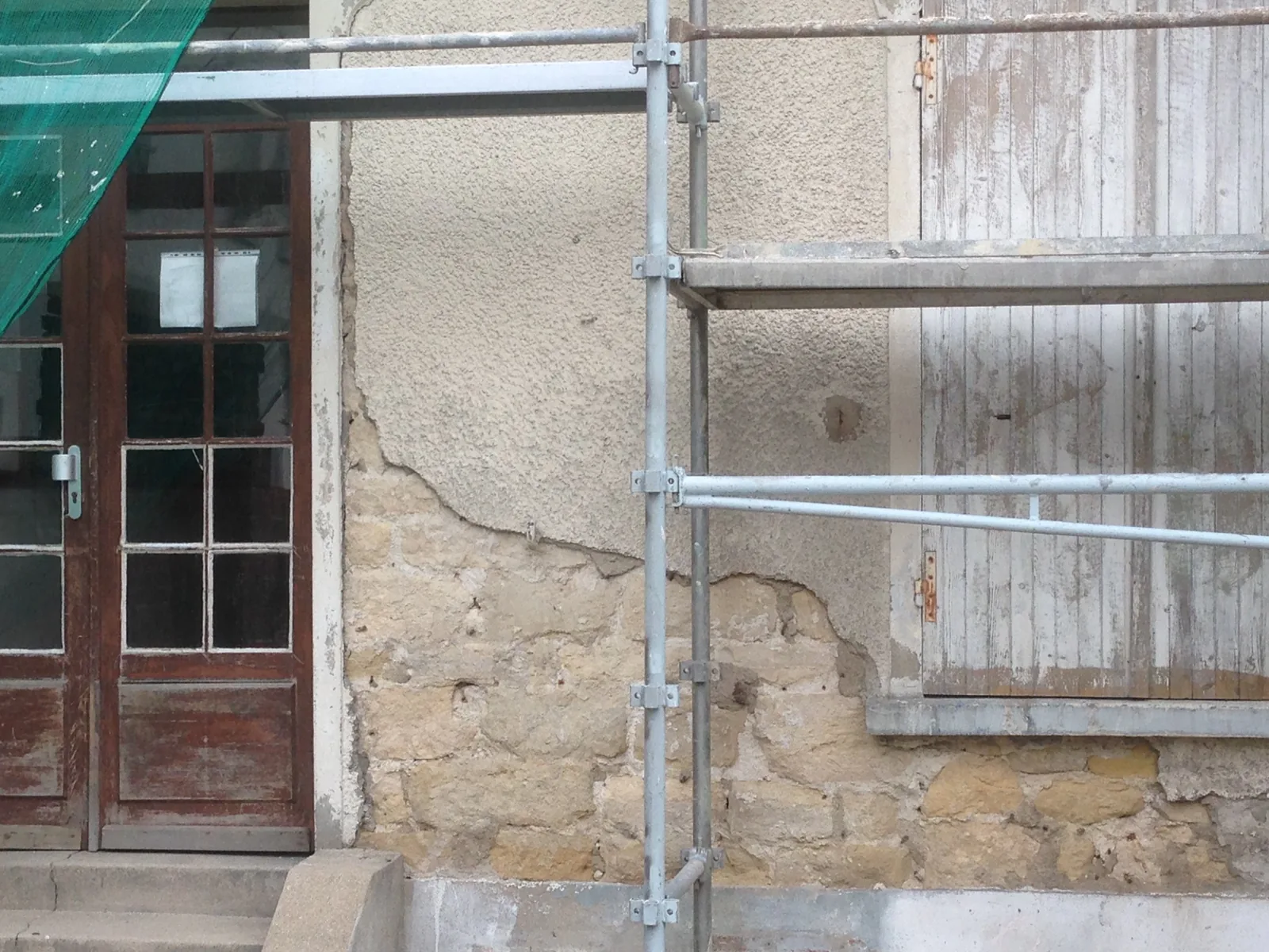 Ancien enduit ciment décollé laissant apparaître la maçonnerie sur une façade de copropriété à Paris 4e avant travaux