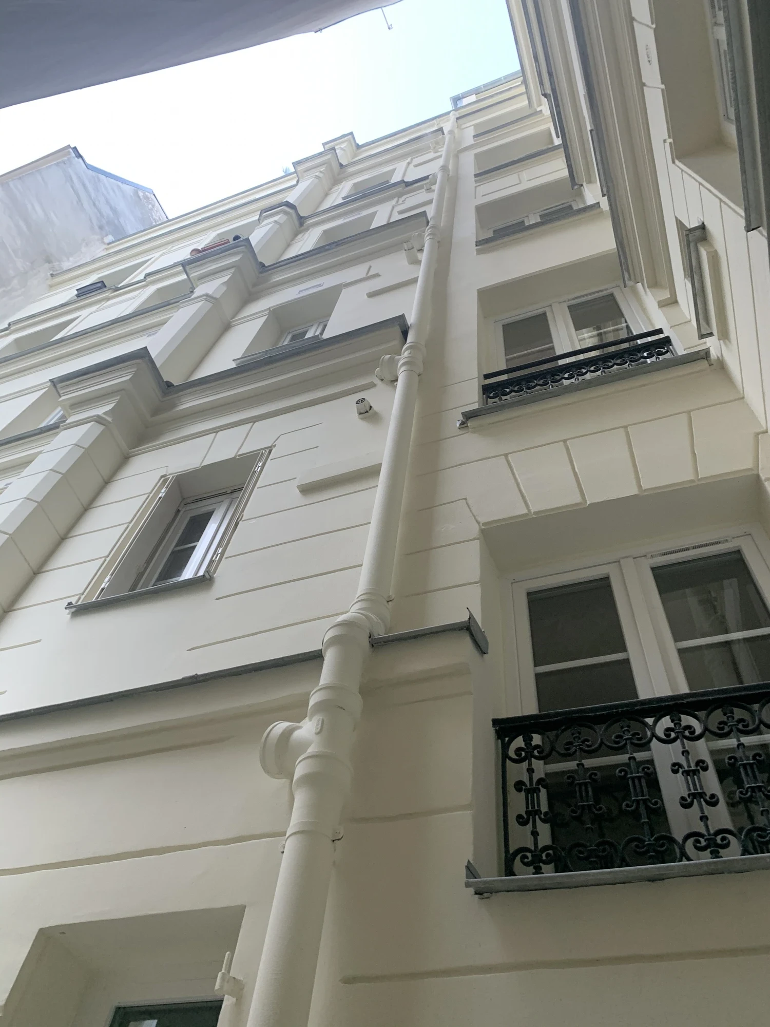 Façade sur cour rénovée d'un immeuble à Paris 5e après ravalement : enduit repris, modénatures et garde-corps en fer forgé
