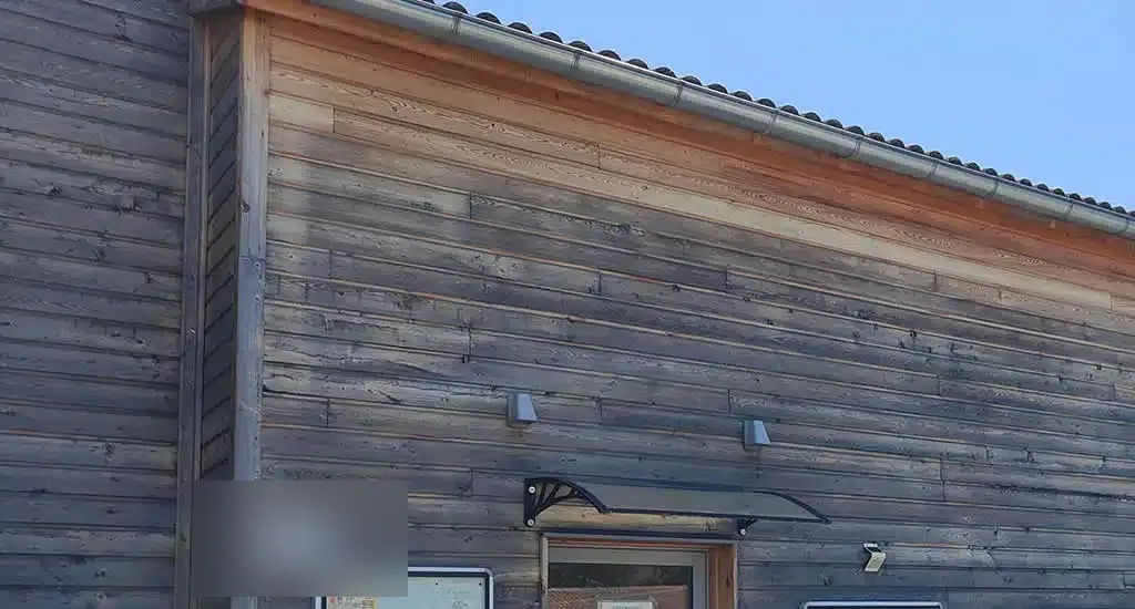 Dégrisage d'un bardage bois en cours : la teinte miel du Red Cedar retrouvée sur la partie traitée