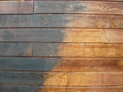 Détail du dégrisage d'un bardage bois : contraste entre la zone grisaillée et la zone traitée