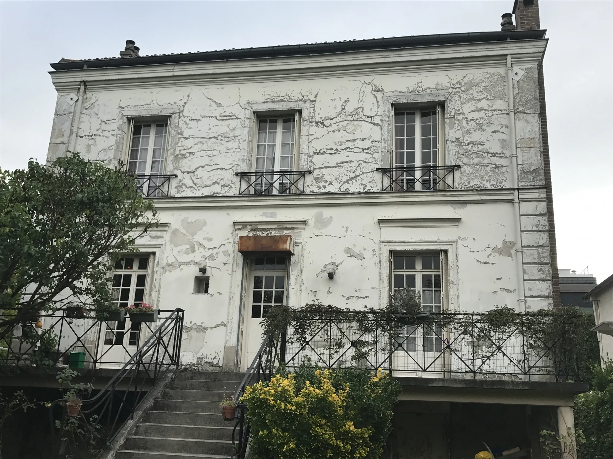 Peinture qui s'écaille et se décolle d'un enduit plâtre-chaux sur une maison des années 1930 à Ville-d'Avray